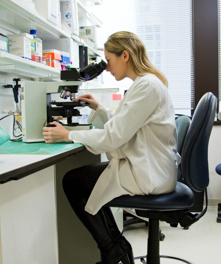 Female scientist in lab looking through microscope